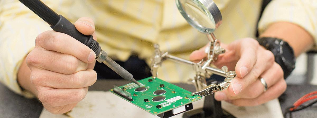 a person's hand holding a soldering device