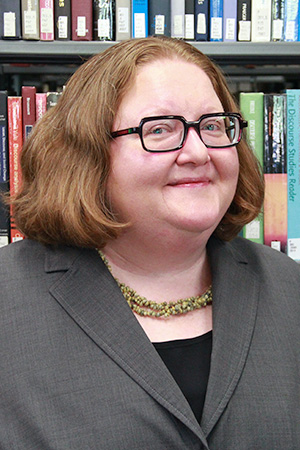 a woman with glasses and red hair smiling at the camera