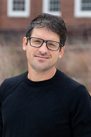 A man wearing glasses and a black shirt looking at the camera