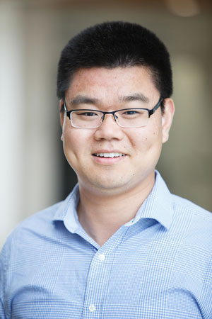 a man wearing glasses and a blue shirt looks at the camera