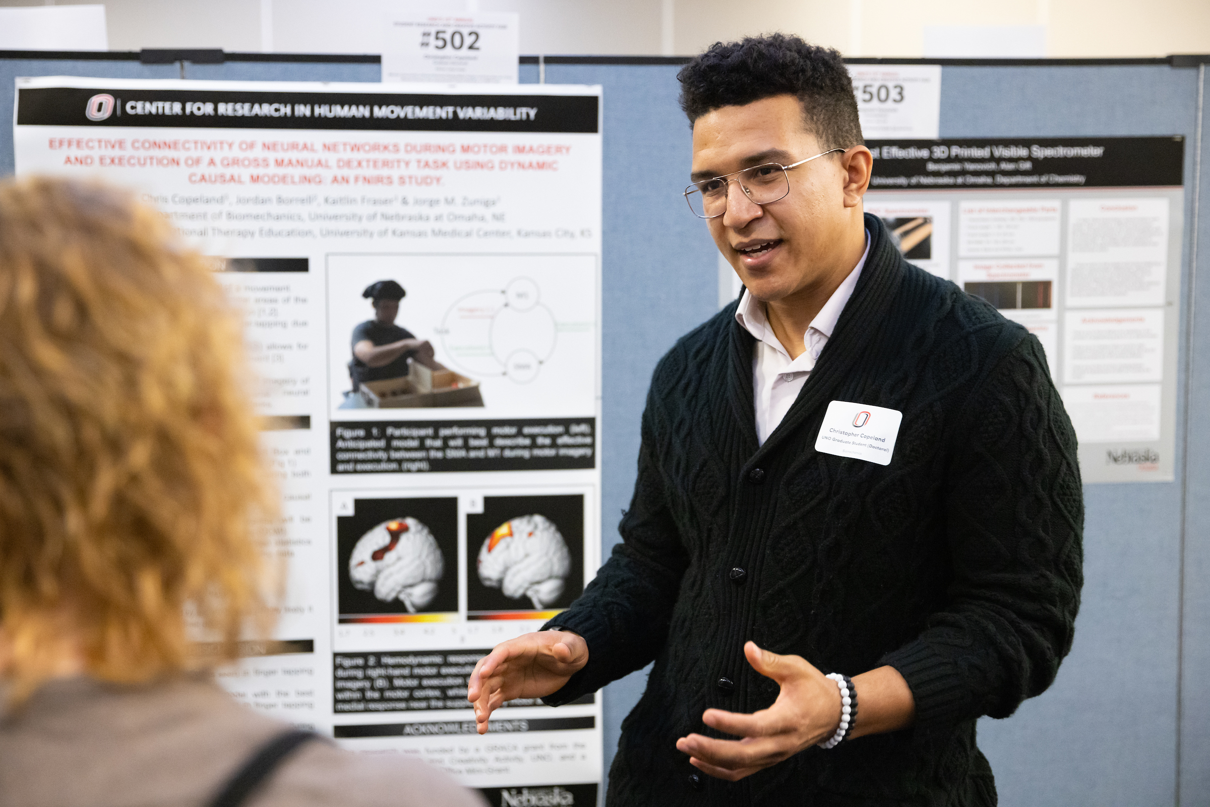 A student wearing glasses and a black sweater presents a poster at the 2023 RCAF