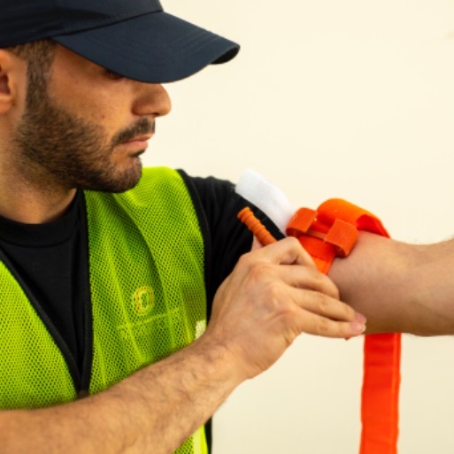 Student placing a tourniquet around their arm during stop the bleed training session