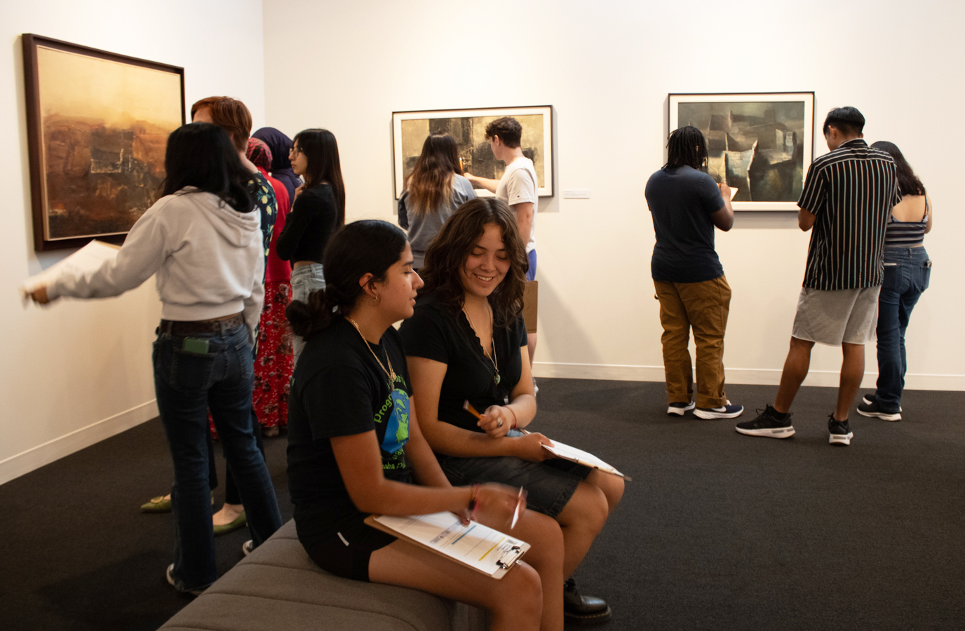 High school students look at paintings in a museum gallery